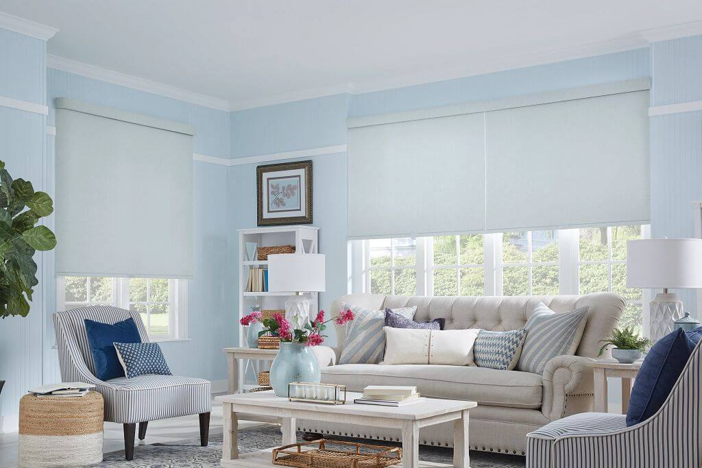 Roller shades in a bright living room, shown in a light neutral fabric